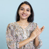 Indian satisfied woman clapping hands and feeling proud of a milestone in studio, pleased and satisfied with an achievement. Smiling adult applauding, saying congratulations for victory.